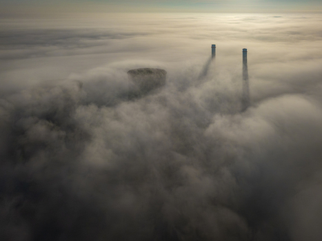 Aerial view of RWE Clauscentrale power plant with cooling towers and tall chimneys emerging through a thick layer of morning fog Maasbracht Limburg Netherlands. Aerial view of RWE Clauscentrale power plant with cooling towers and tall chimneys emerging through a thick layer of morning fog Maasbracht Limburg Netherlands.