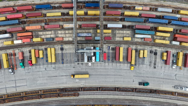 Columbus Ohio United States 24 July 2026 Aerial view of a busy rail yard with colorful shipping containers freight trains and trucks maneuvering on concrete surfaces.