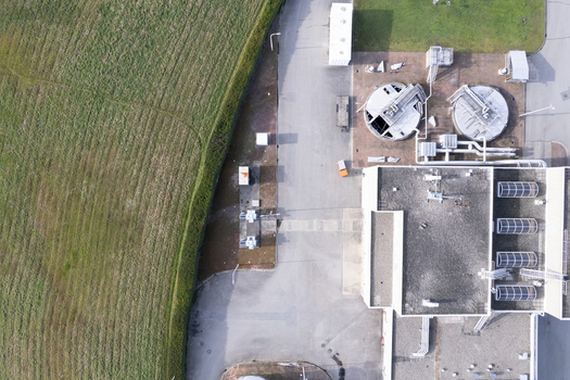 Aerial view of the Waste Water Treatment facility featuring circular sedimentation tanks and industrial buildings adjacent to green fields in Richmond British Columbia Canada. Aerial view of the Waste Water Treatment facility featuring circular sedimentation tanks and industrial buildings adjacent to green fields in Richmond British Columbia Canada.