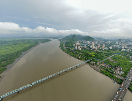 Aerial view of the Thane Creek bridge spanning the river surrounded by lush green landscapes urban residential buildings and a cloudy sky in Thane Maharashtra India. Aerial view of the Thane Creek bridge spanning the river surrounded by lush green landscapes urban residential buildings and a cloudy sky in Thane Maharashtra India.