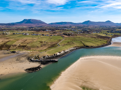 Aerial view of Ballyness Bay with its sandy tidal flats winding coastal road and green fields under a bright blue sky in Ballyness County Donegal Ireland. Aerial view of Ballyness Bay with its sandy tidal flats winding coastal road and green fields under a bright blue sky in Ballyness County Donegal Ireland.
