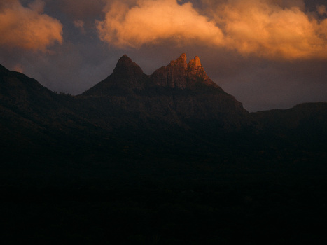 Aerial view of the jagged peaks of Pieter Both mountain illuminated by golden sunset light under dramatic orange clouds in Mauritius Moka District Mauritius. Aerial view of the jagged peaks of Pieter Both mountain illuminated by golden sunset light under dramatic orange clouds in Mauritius Moka District Mauritius.