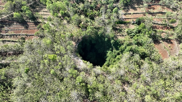 Aerial view of Jomblang Cave surrounded by lush tropical forest and agricultural terraces in Kecamatan Semanu Daerah Istimewa Yogya Indonesia. Aerial view of Jomblang Cave surrounded by lush tropical forest and agricultural terraces in Kecamatan Semanu Daerah Istimewa Yogya Indonesia.