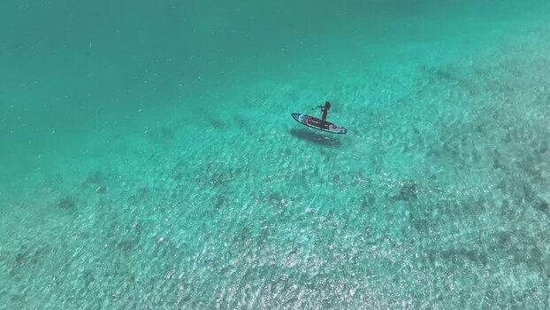 Aerial view of a person paddleboarding in turquoise water Maldives. Aerial view of a person paddleboarding in turquoise water Maldives.