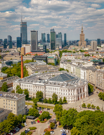 Aerial view of the Warsaw University of Technology Main Building and the city skyline with modern skyscrapers under a cloudy sky in Poland. Aerial view of the Warsaw University of Technology Main Building and the city skyline with modern skyscrapers under a cloudy sky in Poland.