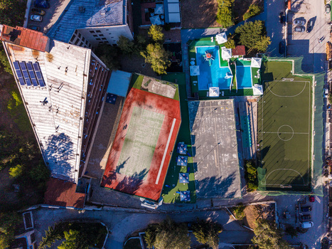 Aerial view of a resort complex featuring a tennis court a swimming pool and a soccer field next to a hotel building in Velingrad Pazardzhik Bulgaria. Aerial view of a resort complex featuring a tennis court a swimming pool and a soccer field next to a hotel building in Velingrad Pazardzhik Bulgaria.