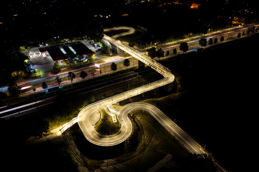 Aerial view of the illuminated Hilde Archenhold Brucke pedestrian bridge winding over a road with light trails at night in Berlin Berlin Germany. Aerial view of the illuminated Hilde Archenhold Brucke pedestrian bridge winding over a road with light trails at night in Berlin Berlin Germany.
