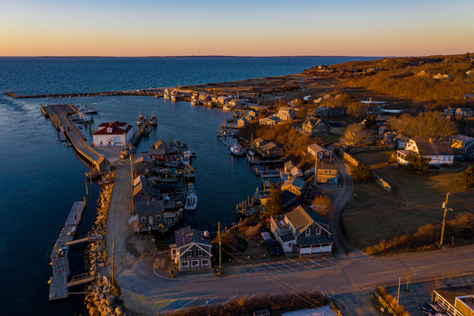 View of Martha s Vineyard featuring the harbor with fishing boats wooden docks and coastal houses during a golden sunset in Edgartown Massachusetts United States.