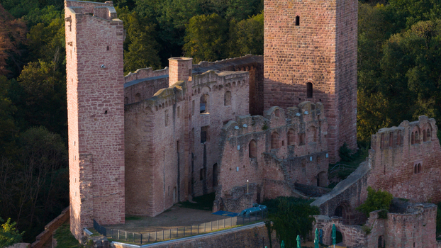 Aerial view of the historic Henneburg castle ruins with its iconic red sandstone towers and walls surrounded by dense forest in Stadtprozelten Bayern Germany.