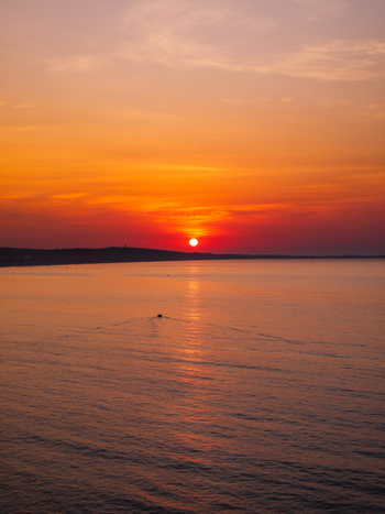 Aerial view of a small boat leaving a wake on the calm sea during a vibrant sunset in Vietnam. Aerial view of a small boat leaving a wake on the calm sea during a vibrant sunset in Vietnam.