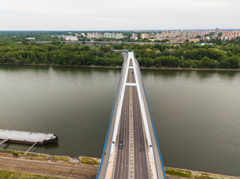 Aerial view of a modern bridge crossing the Danube river with lush green trees on the banks and the city skyline in the background Bratislava Bratislava Region Slovakia. Aerial view of a modern bridge crossing the Danube river with lush green trees on the banks and the city skyline in the background Bratislava Bratislava Region Slovakia.