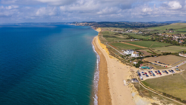 Aerial view of the iconic golden sandstone cliffs along the Jurassic Coast sandy beach and coastal landscape in West Bay England United Kingdom. Aerial view of the iconic golden sandstone cliffs along the Jurassic Coast sandy beach and coastal landscape in West Bay England United Kingdom.