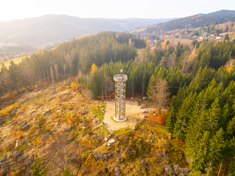 Aerial view of Svetly vrch lookout tower surrounded by dense coniferous forest with autumn foliage and rocky terrain in Albrechtice v Jizerskych horach Liberecky kraj Czechia. Aerial view of Svetly vrch lookout tower surrounded by dense coniferous forest with autumn foliage and rocky terrain in Albrechtice v Jizerskych horach Liberecky kraj Czechia.