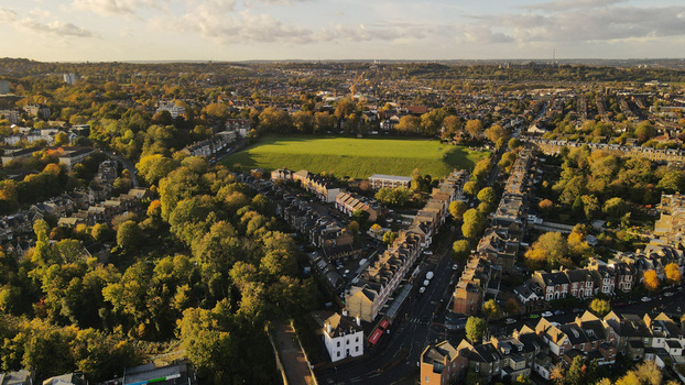 Aerial view of residential streets with terraced houses a large green park and autumn trees London England United Kingdom.
