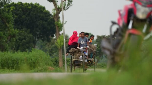 View of people riding a cycle rickshaw on a rural road Bangladesh.