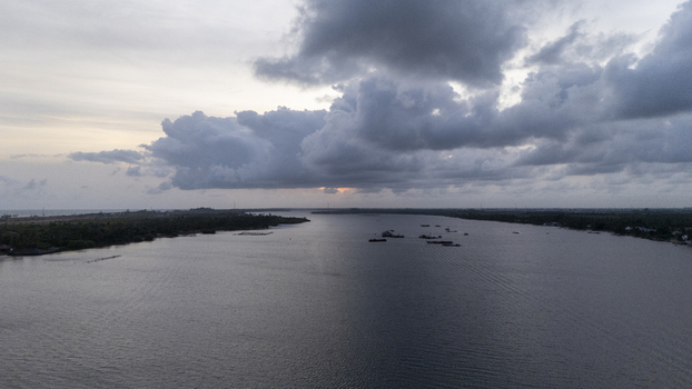 Aerial view of the wide Badagry Creek with small boats scattered on the water under a dramatic cloudy sky at sunset Badagry Lagos Nigeria. Aerial view of the wide Badagry Creek with small boats scattered on the water under a dramatic cloudy sky at sunset Badagry Lagos Nigeria.