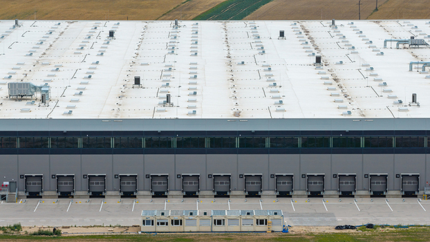 Aerial view of a large warehouse at a distribution center with multiple loading docks and a white roof in Poland.