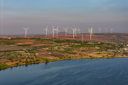Aerial view of the Canh Dong Quat Gio wind farm with white wind turbines on rolling hills near a lake in Phuoc Dinh Ninh Thuan Vietnam. Aerial view of the Canh Dong Quat Gio wind farm with white wind turbines on rolling hills near a lake in Phuoc Dinh Ninh Thuan Vietnam.