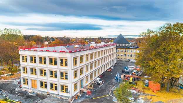Aerial view of a modern building with yellow window frames under construction surrounded by autumn trees in Sweden. Aerial view of a modern building with yellow window frames under construction surrounded by autumn trees in Sweden.