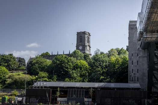 View of the historic tower of St Mary s Church rising above lush green trees with the stone structure of the Tyne Bridge nearby in Newcastle upon Tyne England United Kingdom. View of the historic tower of St Mary s Church rising above lush green trees with the stone structure of the Tyne Bridge nearby in Newcastle upon Tyne England United Kingdom.