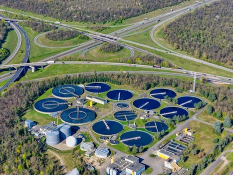 Aerial view of circular water treatment pools contrasting with the green landscape and complex highway interchange Sausheim Grand Est France.