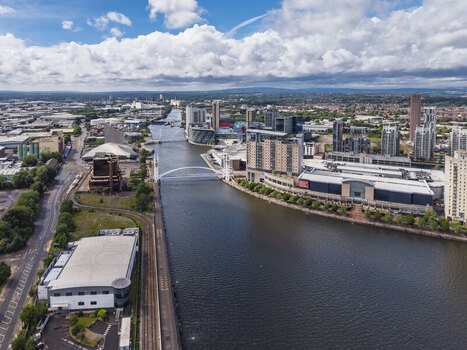 Aerial view of MediaCityUK and the Manchester Ship Canal with modern architecture a pedestrian bridge and waterfront developments in Salford England United Kingdom. Aerial view of MediaCityUK and the Manchester Ship Canal with modern architecture a pedestrian bridge and waterfront developments in Salford England United Kingdom.