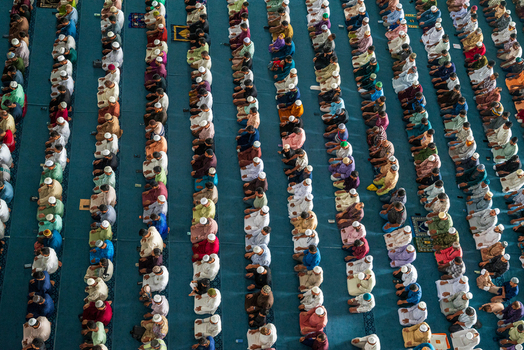 Dhaka Bangladesh 19 June 2026 Aerial view of rows of people praying inside the Baitul Mukarram National Mosque in Dhaka Bangladesh with worshippers kneeling on blue carpets.