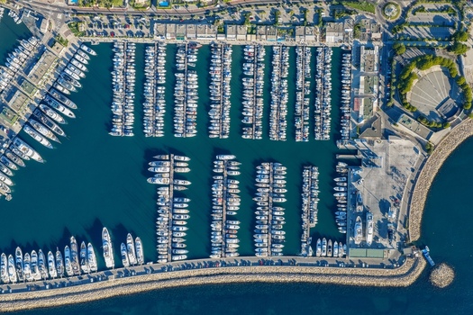Aerial view of the marina filled with yachts and sailboats docked in rows along the piers surrounded by coastal infrastructure in Antibes Provence Alpes Cote d Azur France. Aerial view of the marina filled with yachts and sailboats docked in rows along the piers surrounded by coastal infrastructure in Antibes Provence Alpes Cote d Azur France.