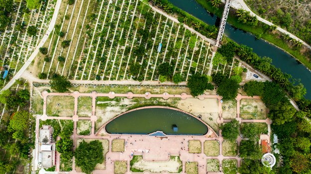 Aerial view of the Rayer Bazaar Martyred Intellectuals Memorial with its curved reflecting pool surrounding landscaped gardens and adjacent cemetery grounds in Dhaka Dhaka Division Bangladesh.