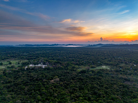 Aerial view of Pidurangala Rock surrounded by dense jungle and distant hills under a vibrant sunset sky in Sigiriya Central Province Sri Lanka. Aerial view of Pidurangala Rock surrounded by dense jungle and distant hills under a vibrant sunset sky in Sigiriya Central Province Sri Lanka.