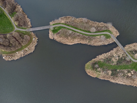Aerial view of interconnected islands with winding paths contrasting the muted browns of dormant vegetation with the cool blues of surrounding water Overgooi Flevoland Netherlands. Aerial view of interconnected islands with winding paths contrasting the muted browns of dormant vegetation with the cool blues of surrounding water Overgooi Flevoland Netherlands.
