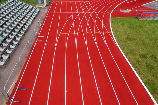 Aerial view of a red running track with white lane markings and stadium bleachers in Vilnius County Lithuania. Aerial view of a red running track with white lane markings and stadium bleachers in Vilnius County Lithuania.