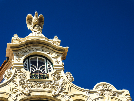 View of the ornate Art Nouveau facade featuring a stone eagle sculpture and intricate floral carvings against a clear blue sky in Aveiro Aveiro District Portugal.