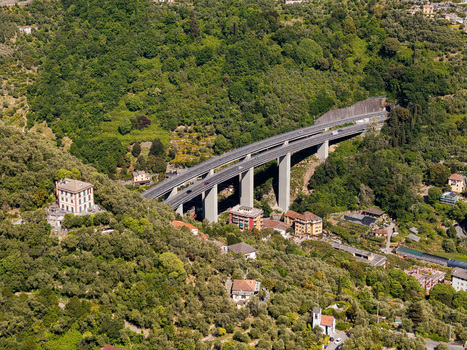 Aerial view of the A12 highway viaduct spanning across a lush green valley with residential buildings and dense Mediterranean vegetation in Genova Liguria Italy. Aerial view of the A12 highway viaduct spanning across a lush green valley with residential buildings and dense Mediterranean vegetation in Genova Liguria Italy.