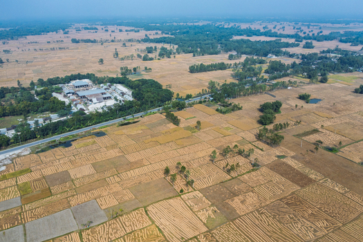 Aerial view of agricultural fields with harvested crops a road and a small industrial complex in Panchagarh Rangpur Division Bangladesh. Aerial view of agricultural fields with harvested crops a road and a small industrial complex in Panchagarh Rangpur Division Bangladesh.