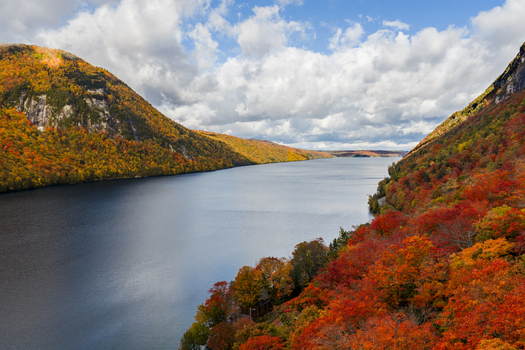 Aerial view of Lake Willoughby surrounded by vibrant autumn foliage on the mountains under a partly cloudy sky in Westmore Vermont United States. Aerial view of Lake Willoughby surrounded by vibrant autumn foliage on the mountains under a partly cloudy sky in Westmore Vermont United States.