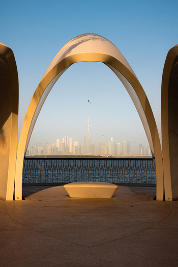 View of the Burj Khalifa and Dubai skyline framed by a modern white archway at Dubai Creek Harbour during golden hour Dubai Dubai United Arab Emirates. View of the Burj Khalifa and Dubai skyline framed by a modern white archway at Dubai Creek Harbour during golden hour Dubai Dubai United Arab Emirates.
