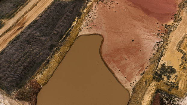 Aerial view of industrial salt mining patterns with a large brown pond and textured red earth in Kalbarri Western Australia Australia. Aerial view of industrial salt mining patterns with a large brown pond and textured red earth in Kalbarri Western Australia Australia.