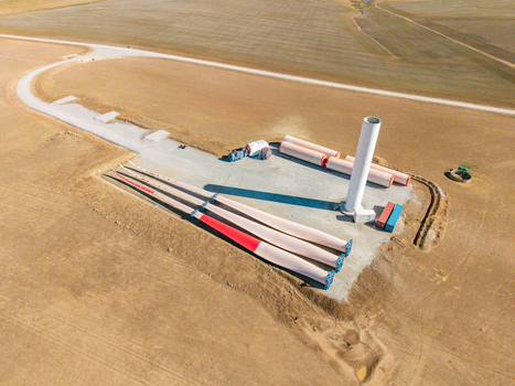 Aerial view of a wind turbine construction site featuring large blades and a tower section in a rural field Swellendam Western Cape South Africa. Aerial view of a wind turbine construction site featuring large blades and a tower section in a rural field Swellendam Western Cape South Africa.