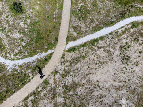 Aerial view of a solitary figure walking along a winding path through the dunes contrasting with the arid landscape Duinvalleiweg Almere Flevoland Netherlands.