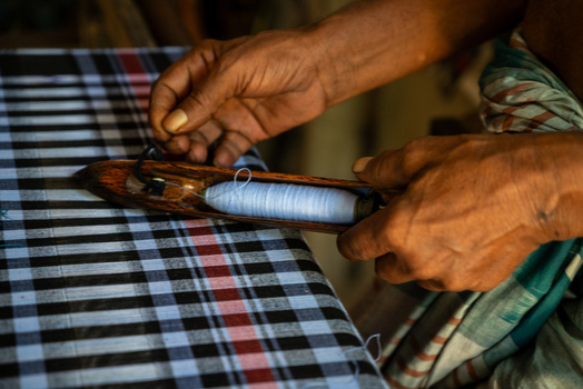 Joypurhat Rajshahi Division Bangladesh 22 September 2026 View of a weaver using a wooden shuttle to weave traditional checkered fabric. Joypurhat Rajshahi Division Bangladesh 22 September 2026 View of a weaver using a wooden shuttle to weave traditional checkered fabric.