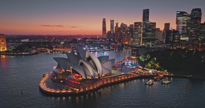 Aerial view of Sydney Opera House at dusk with the illuminated city skyline in the background Sydney New South Wales Australia. Aerial view of Sydney Opera House at dusk with the illuminated city skyline in the background Sydney New South Wales Australia.