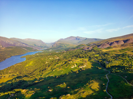 Aerial view of the lush green landscape surrounding Llyn Padarn with rolling hills winding roads and distant mountains in Cwm y glo Wales United Kingdom. Aerial view of the lush green landscape surrounding Llyn Padarn with rolling hills winding roads and distant mountains in Cwm y glo Wales United Kingdom.