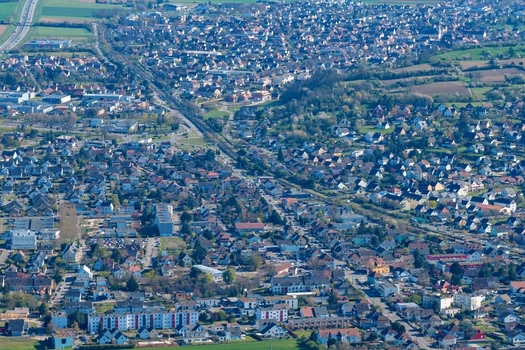 Aerial view of a sprawling town where buildings and houses are nestled among trees creating a diverse urban landscape Sausheim Grand Est France.