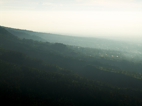 Aerial view of the lush green slopes of Mount Merapi near Bunker Kaliadem with dense tropical forests shrouded in morning mist Kecamatan Pakem Daerah Istimewa Yogya Indonesia. Aerial view of the lush green slopes of Mount Merapi near Bunker Kaliadem with dense tropical forests shrouded in morning mist Kecamatan Pakem Daerah Istimewa Yogya Indonesia.