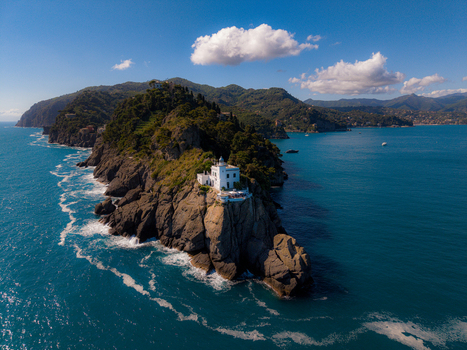 Aerial view of the Faro di Portofino lighthouse perched on a rocky cliff overlooking the Mediterranean Sea in Portofino Liguria Italy.