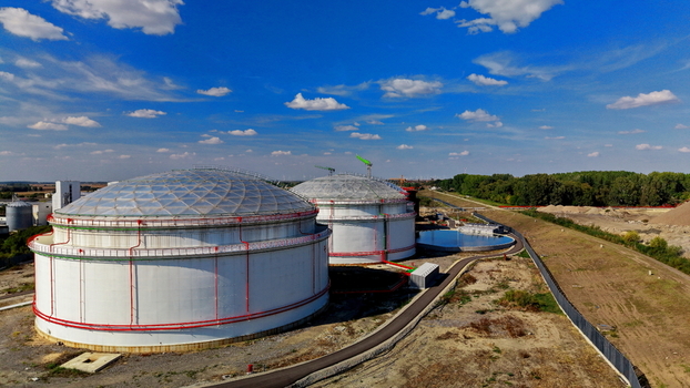 Aerial view of large white oil storage tanks with domed roofs surrounded by industrial infrastructure and green fields under a blue sky in Kovin Vojvodina Serbia. Aerial view of large white oil storage tanks with domed roofs surrounded by industrial infrastructure and green fields under a blue sky in Kovin Vojvodina Serbia.