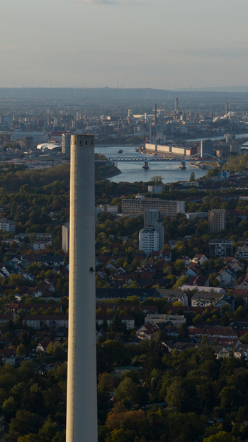 Aerial view of the Grosskraftwerk Mannheim power plant chimney rising above the urban landscape with the Rhine river and bridge in Mannheim Baden Wurttemberg Germany.