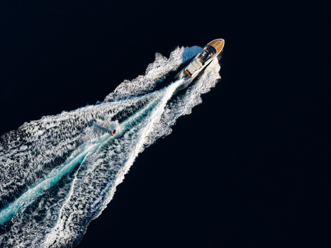 Aerial view of a motorboat pulling a wakeboarder through the deep blue waters of the Mediterranean Sea near Le Trayas in Saint Raphael Provence Alpes Cote d Azur France. Aerial view of a motorboat pulling a wakeboarder through the deep blue waters of the Mediterranean Sea near Le Trayas in Saint Raphael Provence Alpes Cote d Azur France.