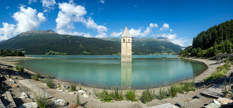 View of the historic submerged bell tower of Reschensee standing in the turquoise water surrounded by lush green mountains Graun im Vinschgau Trentino South Tyrol Italy. View of the historic submerged bell tower of Reschensee standing in the turquoise water surrounded by lush green mountains Graun im Vinschgau Trentino South Tyrol Italy.